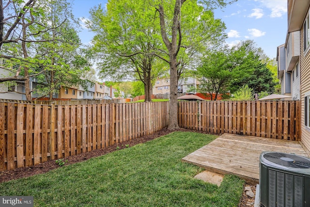 view of yard with a wooden deck, a fenced backyard, central AC unit, and a residential view