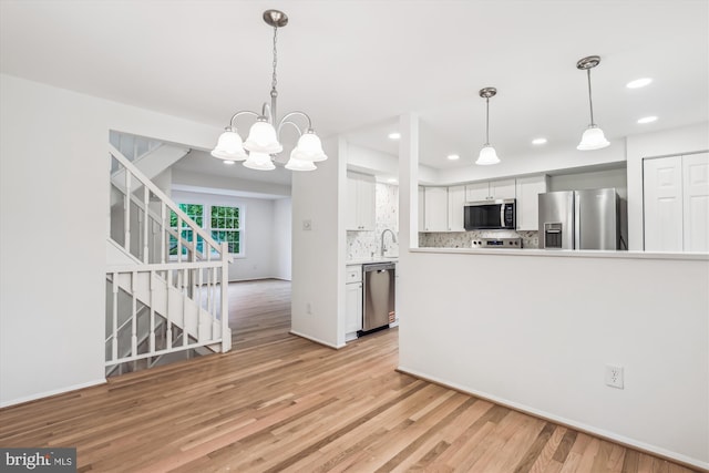 kitchen with recessed lighting, a sink, decorative backsplash, light wood-style floors, and appliances with stainless steel finishes