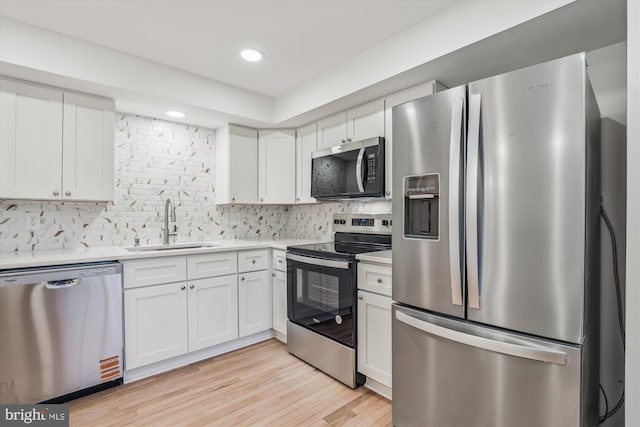 kitchen with white cabinetry, decorative backsplash, a sink, appliances with stainless steel finishes, and light countertops
