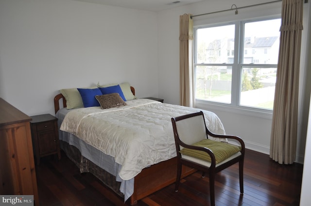 bedroom with baseboards and dark wood-type flooring