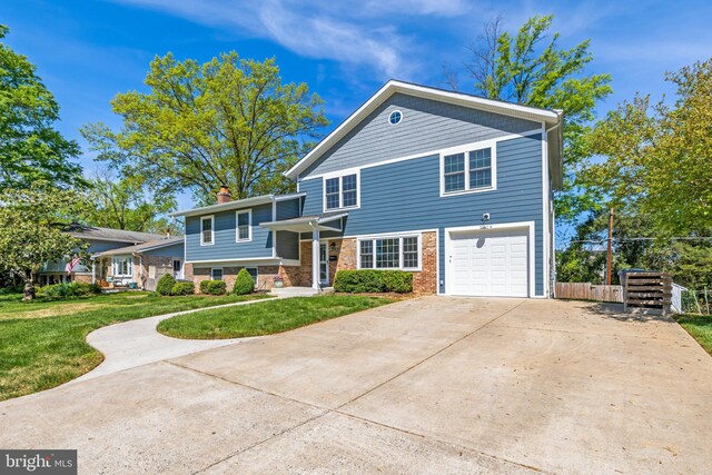 2314 Apple Hill Rd, Alexandria, VA 22308 - tri-level home with driveway, a chimney, an attached garage, brick siding, and a front lawn
