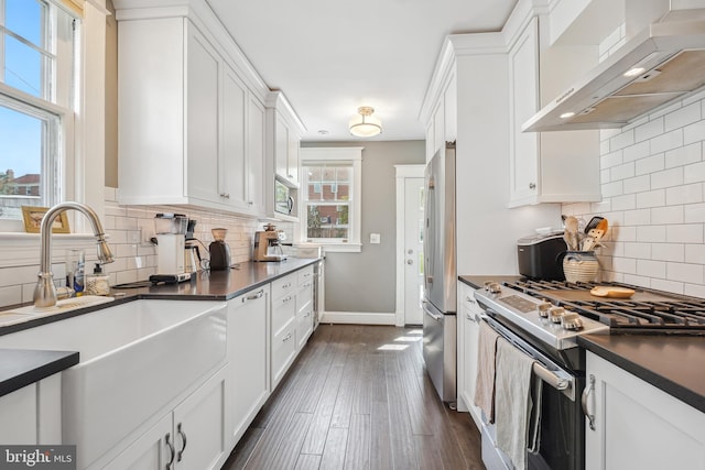 kitchen featuring stainless steel appliances, wall chimney exhaust hood, and white cabinetry