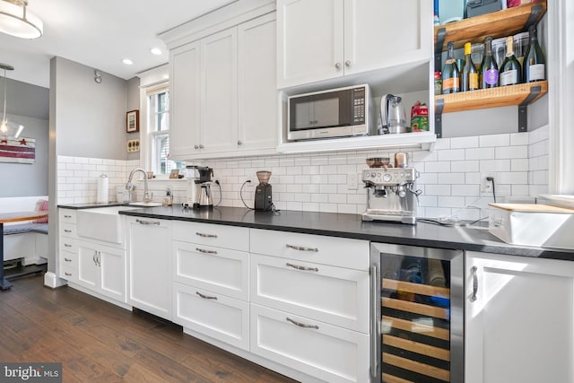 kitchen with dark wood-style flooring, wine cooler, dark countertops, and stainless steel microwave