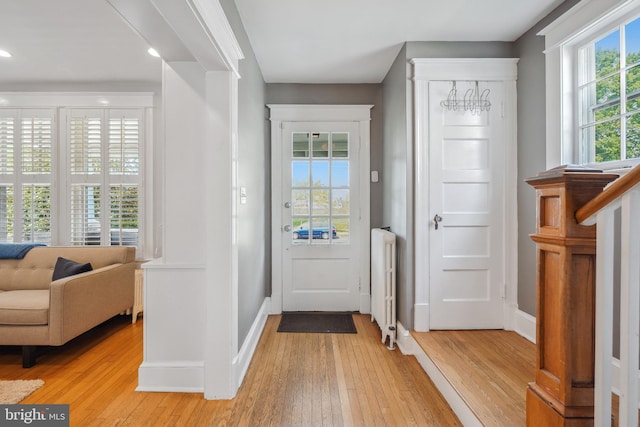 foyer entrance featuring baseboards, light wood-style flooring, and radiator