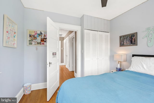 bedroom featuring baseboards, a ceiling fan, light wood finished floors, and a closet