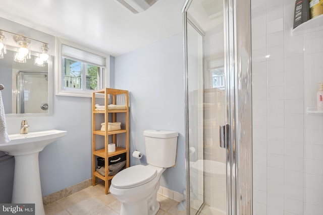 bathroom with toilet, baseboards, a shower stall, and tile patterned flooring