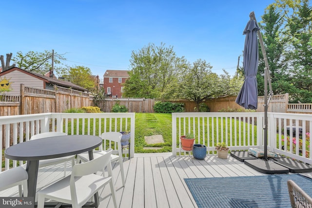 deck featuring a lawn, outdoor dining area, and a fenced backyard