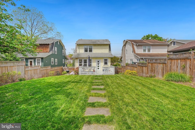 rear view of property featuring a lawn, a fenced backyard, and a deck