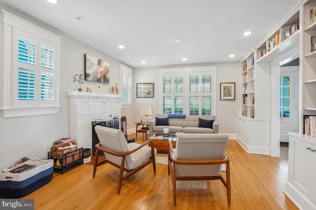 living area featuring recessed lighting, baseboards, a fireplace, and light wood-type flooring