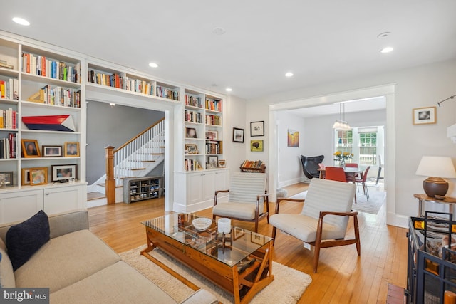 living area with stairs, built in features, baseboards, light wood-type flooring, and recessed lighting