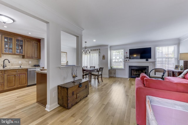 living area featuring a fireplace, light wood-style floors, crown molding, and baseboards