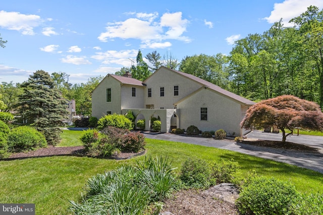 view of front of home with stucco siding, a front yard, and a chimney