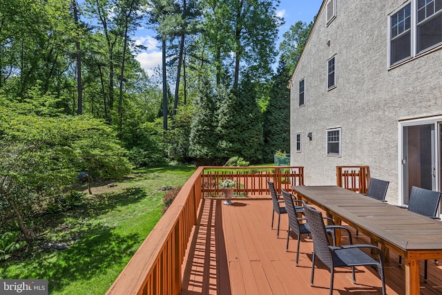 deck featuring outdoor dining space and a lawn