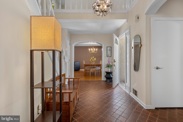foyer entrance featuring a chandelier, arched walkways, and baseboards