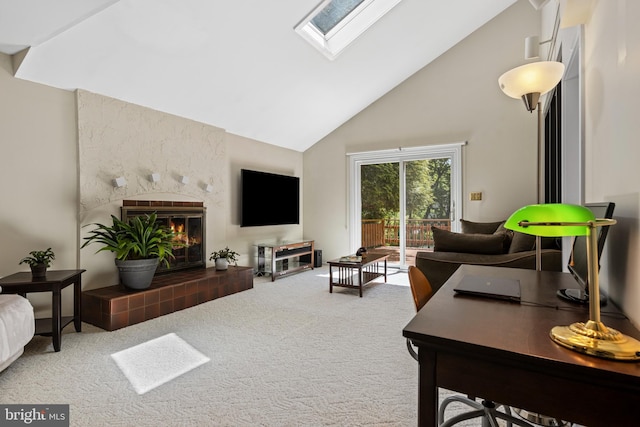 living room featuring high vaulted ceiling, carpet, a tiled fireplace, a skylight, and a desk