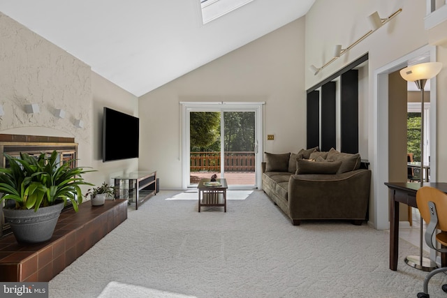 living area with high vaulted ceiling, carpet, and a fireplace