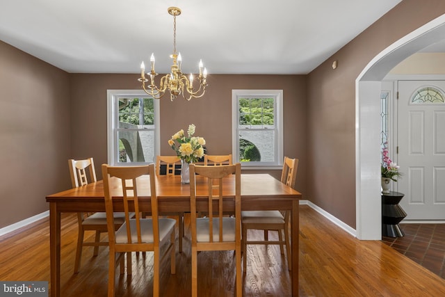 dining room with arched walkways, healthy amount of natural light, baseboards, and a chandelier