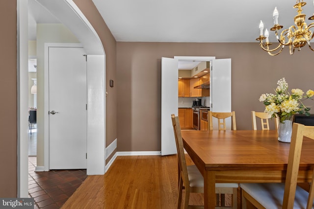 dining room with arched walkways, a chandelier, and baseboards