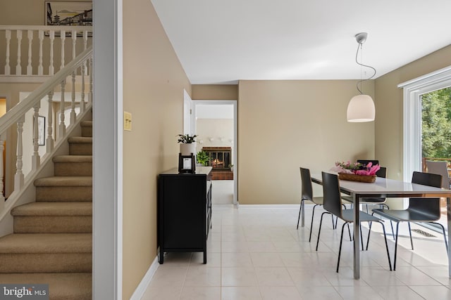 dining area featuring stairway, baseboards, and a glass covered fireplace