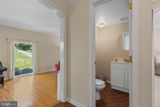 half bath with vanity, toilet, and baseboards