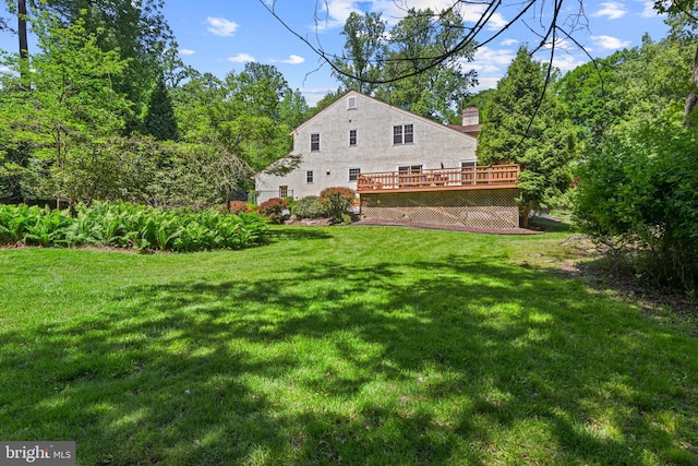 back of house featuring a deck, a yard, and a chimney
