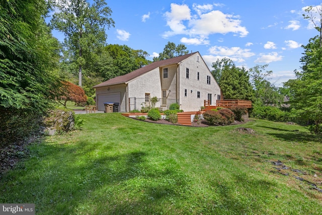 view of side of property with a garage, a lawn, a deck, and stucco siding