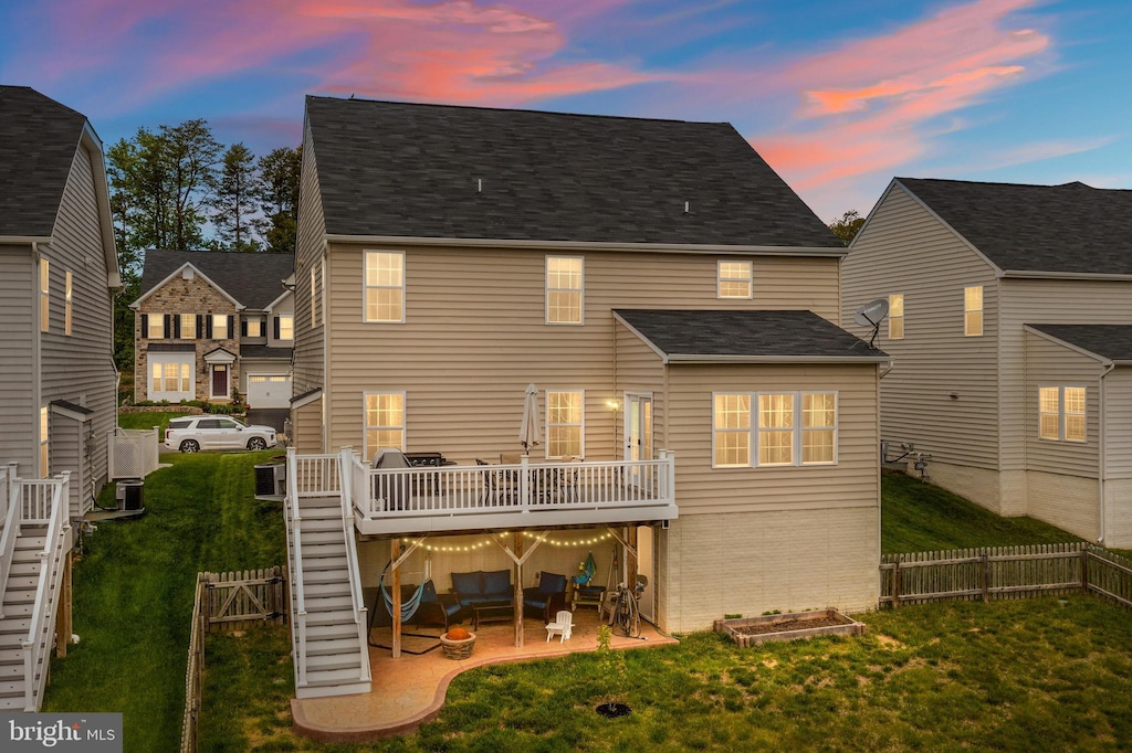 rear view of property featuring a patio, a wooden deck, a yard, and a fenced backyard