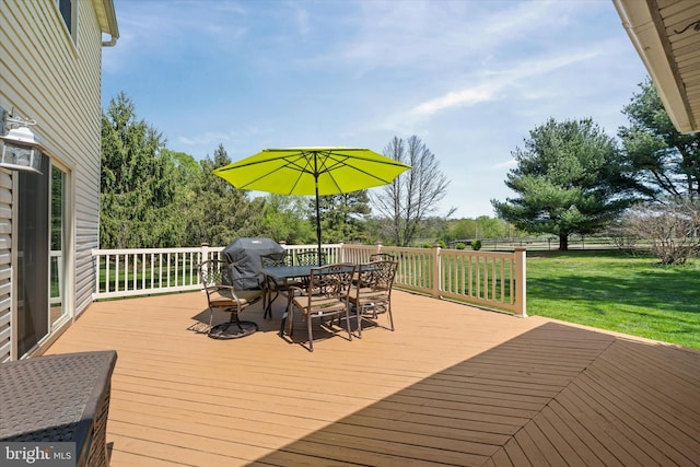 wooden terrace featuring grilling area, a yard, and outdoor dining space
