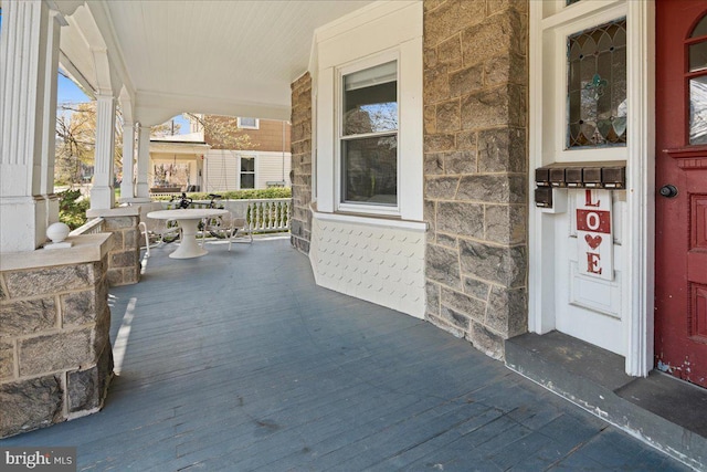 property entrance featuring covered porch and stone siding