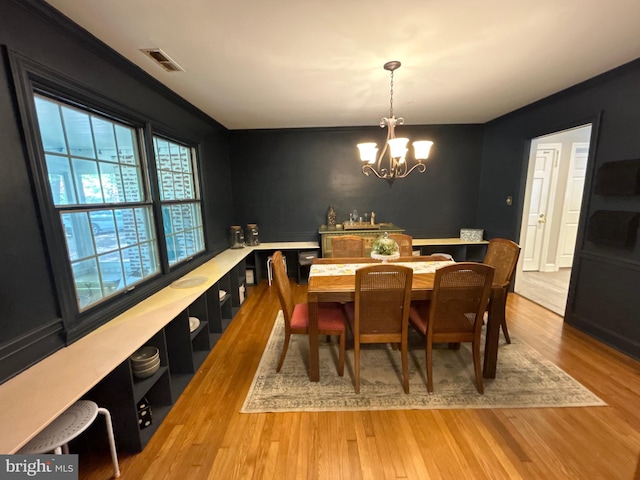 dining space featuring visible vents, light wood-style flooring, and a notable chandelier