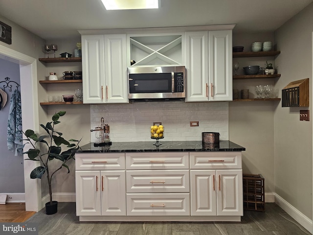 bar with wood finished floors, stainless steel microwave, baseboards, and tasteful backsplash