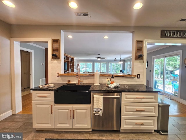 kitchen featuring stainless steel dishwasher, decorative backsplash, recessed lighting, white cabinets, and a sink