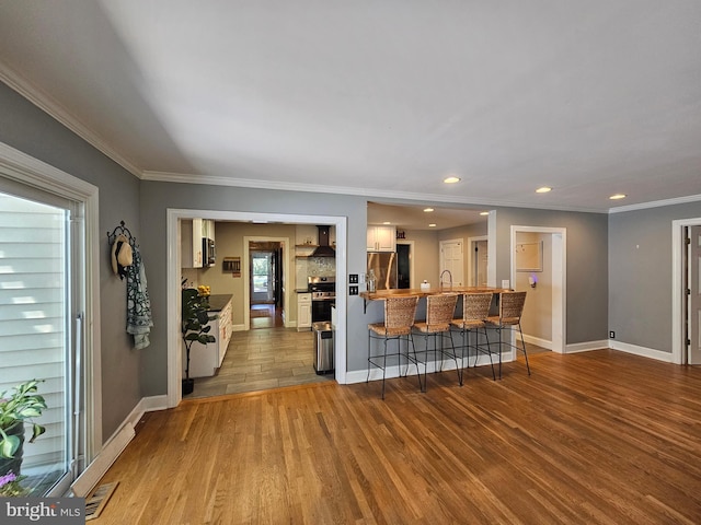 living area featuring crown molding, recessed lighting, baseboards, and wood finished floors