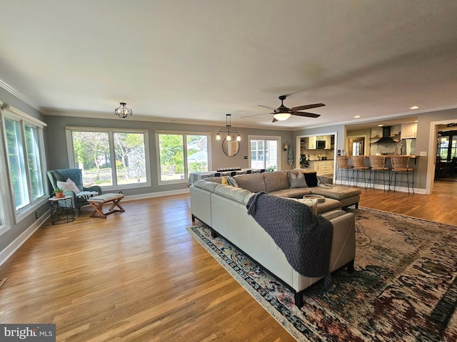 living room with recessed lighting, baseboards, ornamental molding, and light wood-style flooring