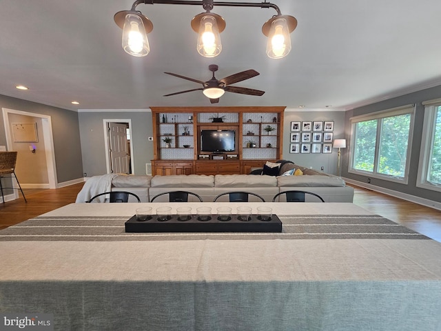 living room with crown molding, a ceiling fan, baseboards, recessed lighting, and wood finished floors