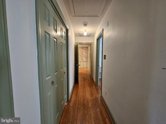 hallway featuring baseboards, visible vents, attic access, and dark wood-type flooring