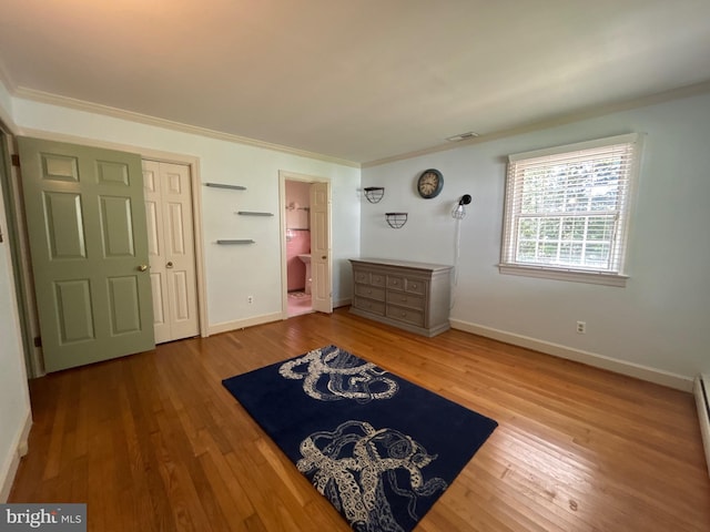 unfurnished bedroom with visible vents, ornamental molding, baseboards, and wood finished floors