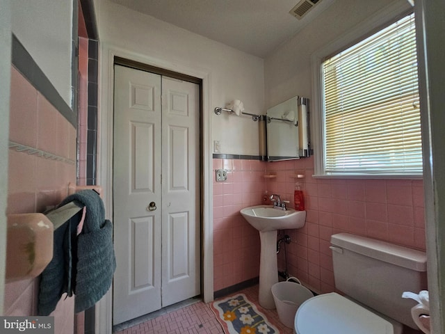 bathroom featuring tile walls, a closet, toilet, and visible vents