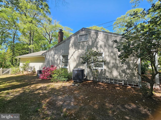 view of property exterior featuring central AC unit and a chimney