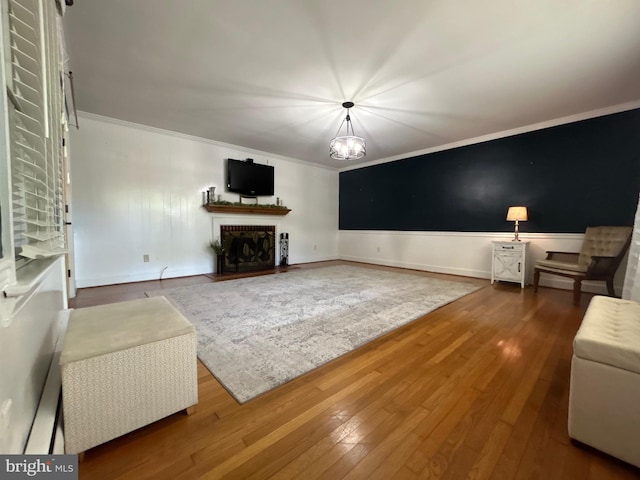 unfurnished living room with crown molding, a fireplace with flush hearth, baseboards, and hardwood / wood-style flooring