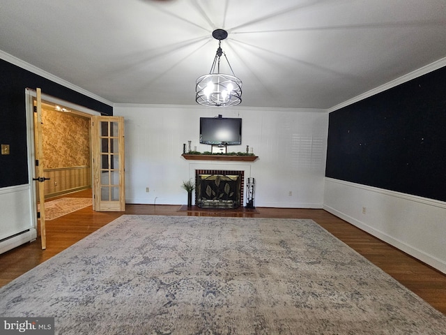 living room featuring crown molding, a wainscoted wall, a brick fireplace, and wood finished floors