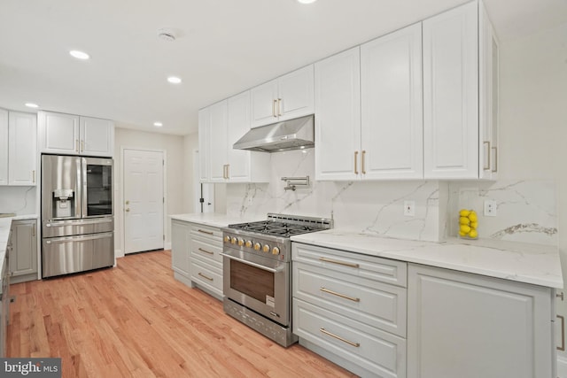 kitchen featuring recessed lighting, white cabinetry, under cabinet range hood, tasteful backsplash, and stainless steel appliances