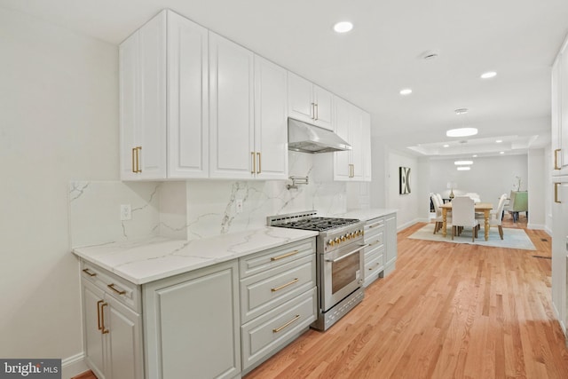 kitchen featuring high end stainless steel range oven, light wood-type flooring, baseboards, under cabinet range hood, and recessed lighting
