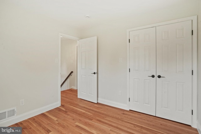 unfurnished bedroom with light wood-style floors, baseboards, a closet, and visible vents