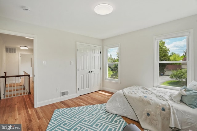 bedroom featuring baseboards, visible vents, multiple windows, and light wood-type flooring