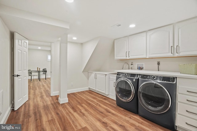 laundry area with washing machine and clothes dryer, cabinet space, light wood finished floors, recessed lighting, and baseboards