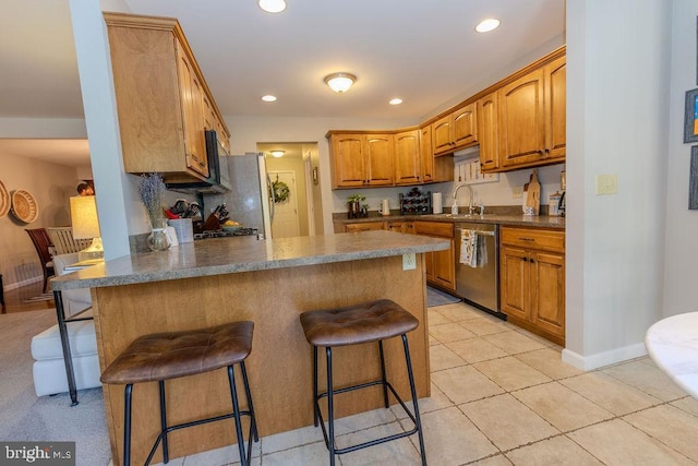 kitchen with dark countertops, a kitchen bar, a peninsula, and stainless steel appliances