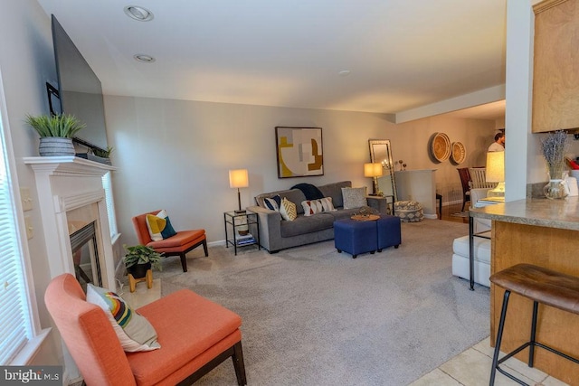 living room with a high end fireplace, light colored carpet, and baseboards