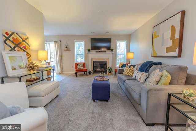 living area with baseboards, a fireplace with flush hearth, and carpet flooring