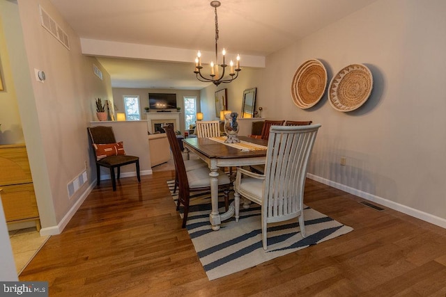 dining space featuring visible vents, wood finished floors, and a chandelier